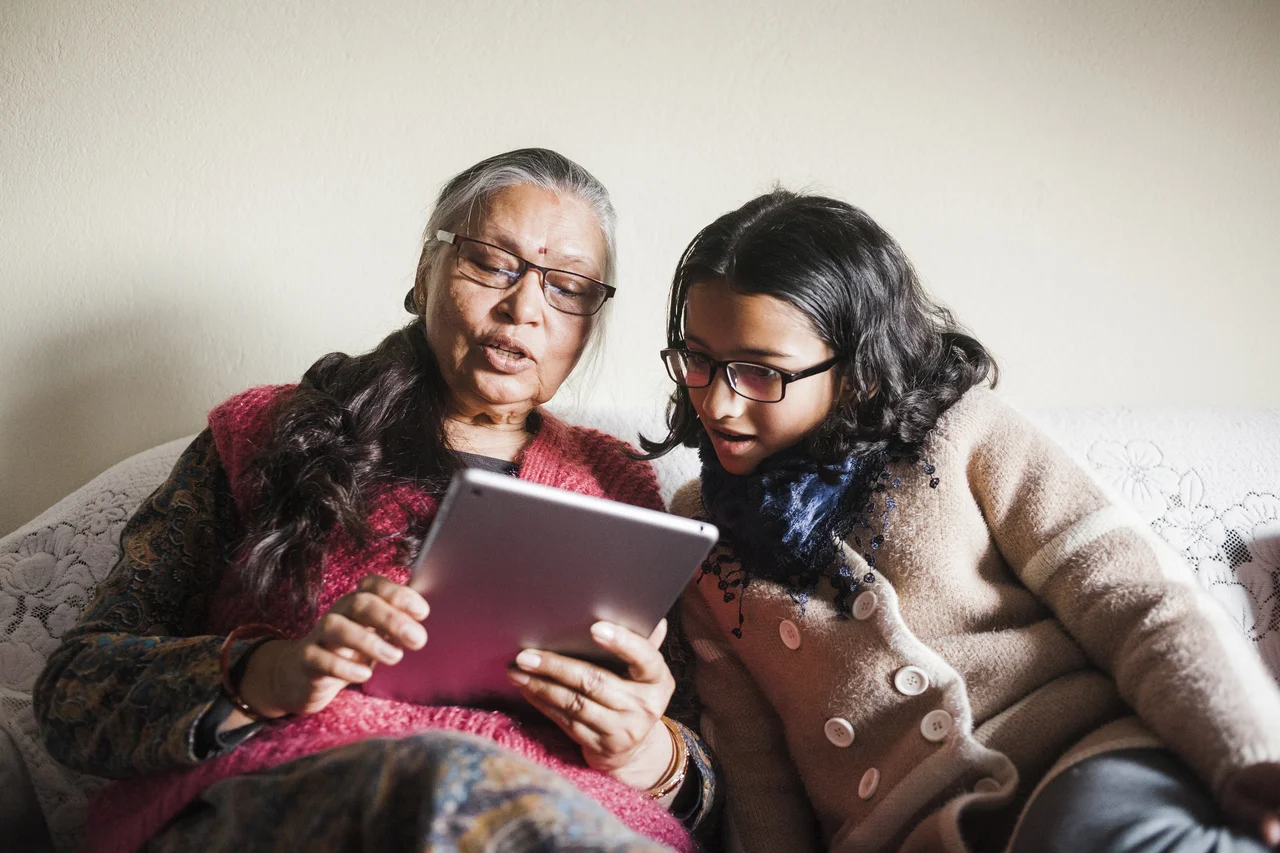 An eldery woman getting help on her tablet from her daughter